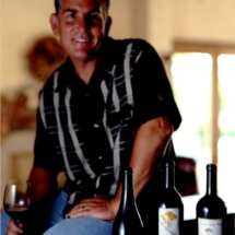 steve reynolds sitting with glass of wine and bottles